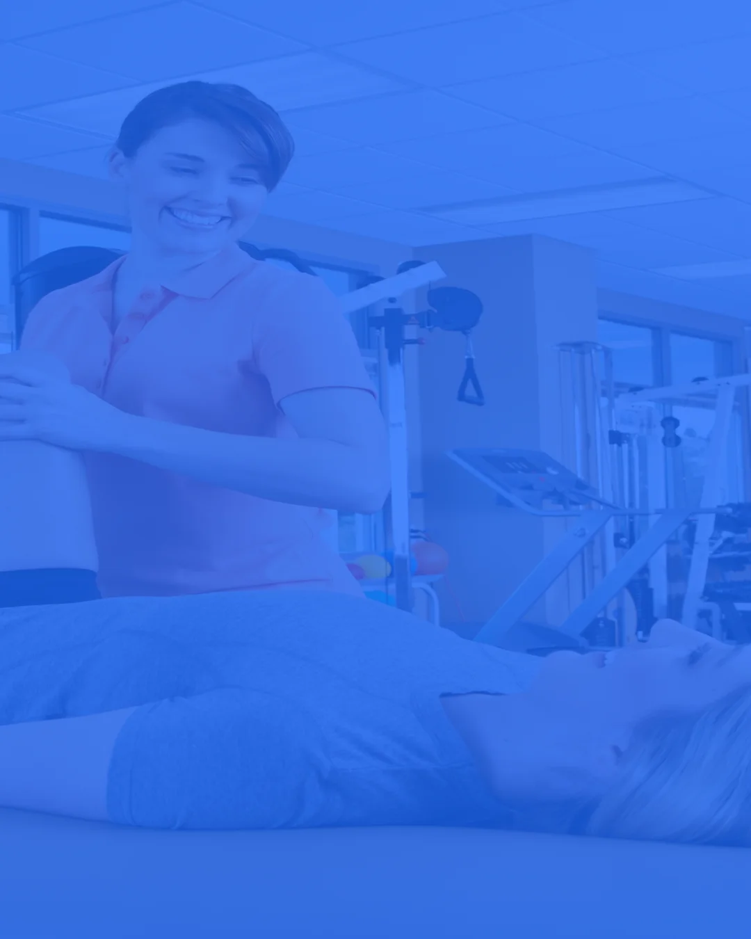 Profissional de fisioterapia caminha com utente num ginásio clínico.